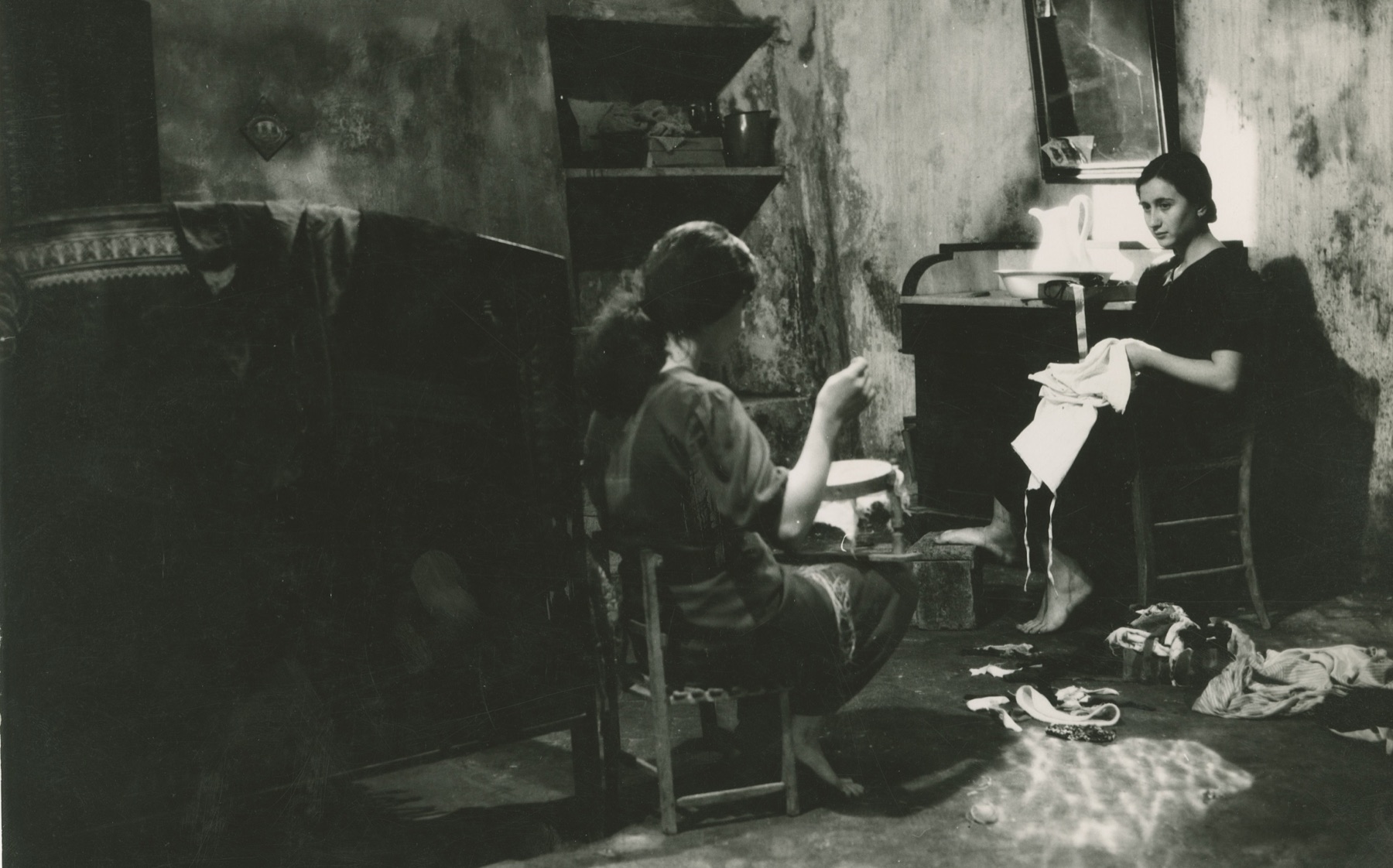 Filmstill uit La terra trema (1948): twee vrouwen in gesprek in een eenvoudige kamer in Sicilië.